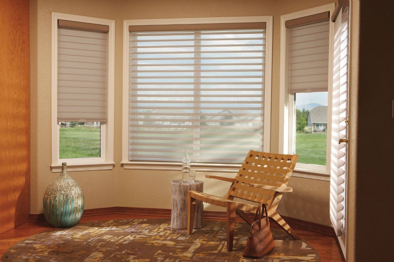 Small sitting corner with a woven chair and a corner window outfitted with Silhouette® Sheer Shades from Hunter Douglas at Enhancing Windows near DAYTON, OH
